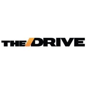 Logo of 'The Drive,' featuring the words 'THE' and 'DRIVE' in black, with a stylized orange line across the 'D' in 'DRIVE.' The design is bold and modern.